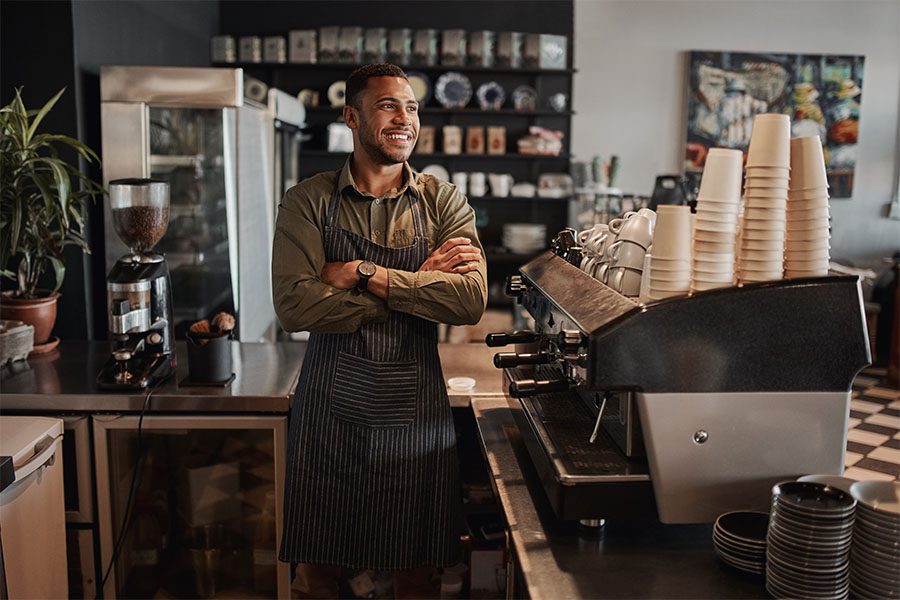 Business Insurance - Portrait of Happy Coffee Shop Owner Standing Behind the Counter